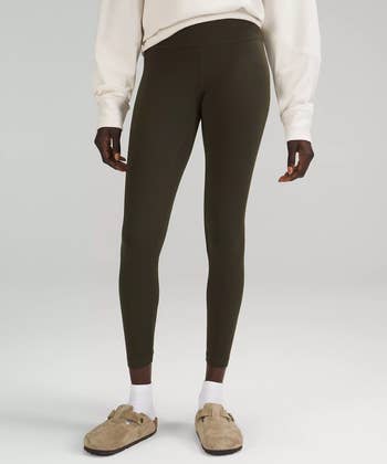 Model wearing the leggings in dark olive with white sweatshirt