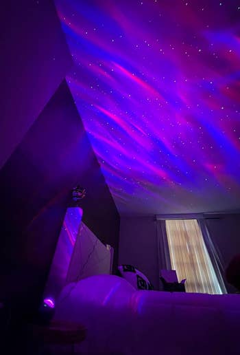 a reviewer photo of the projector casting pink and purple light onto their bedroom ceiling