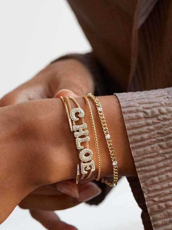a model wearing a gold bracelet that says chloe in pave stone covered letters