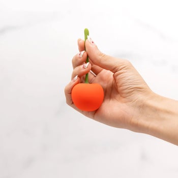 Hand holding red cherry-shaped vibrator