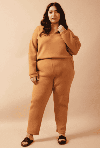a model wearing the pants in a a caramel color with a matching top