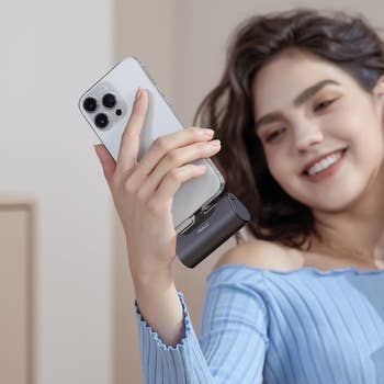model holding a phone with the lipstick-sized charger attached to the bottom 