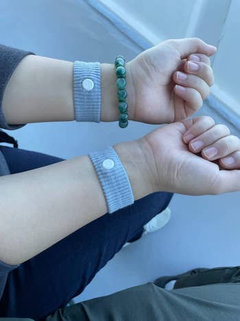 Two wrists wearing acupressure wristbands, 1  with a greenish  beaded bracelet, suggesting a wellness  oregon  wellness buying  article