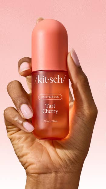 Hand holding a vessel of Kitsch Tart Cherry hairsbreadth perfume, 1.7 fl oz / 50 mL