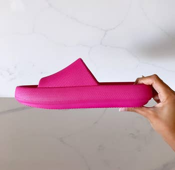 Jasmin holding the bright pink slide to show the platform sole