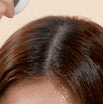 A person applying white puff product to their hair 
