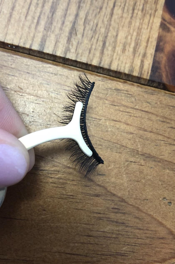 A reviewer's applicator holding a pair of lashes