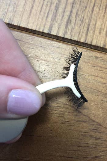 A reviewer's applicator holding a pair of lashes