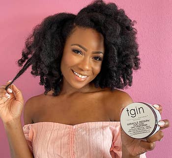 Model with healthy-looking curls and holding the product