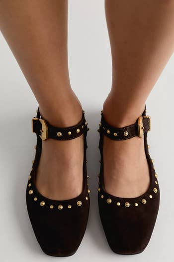 Brown suede flats with golden studs and buckle straps, shown worn, featured successful buying article