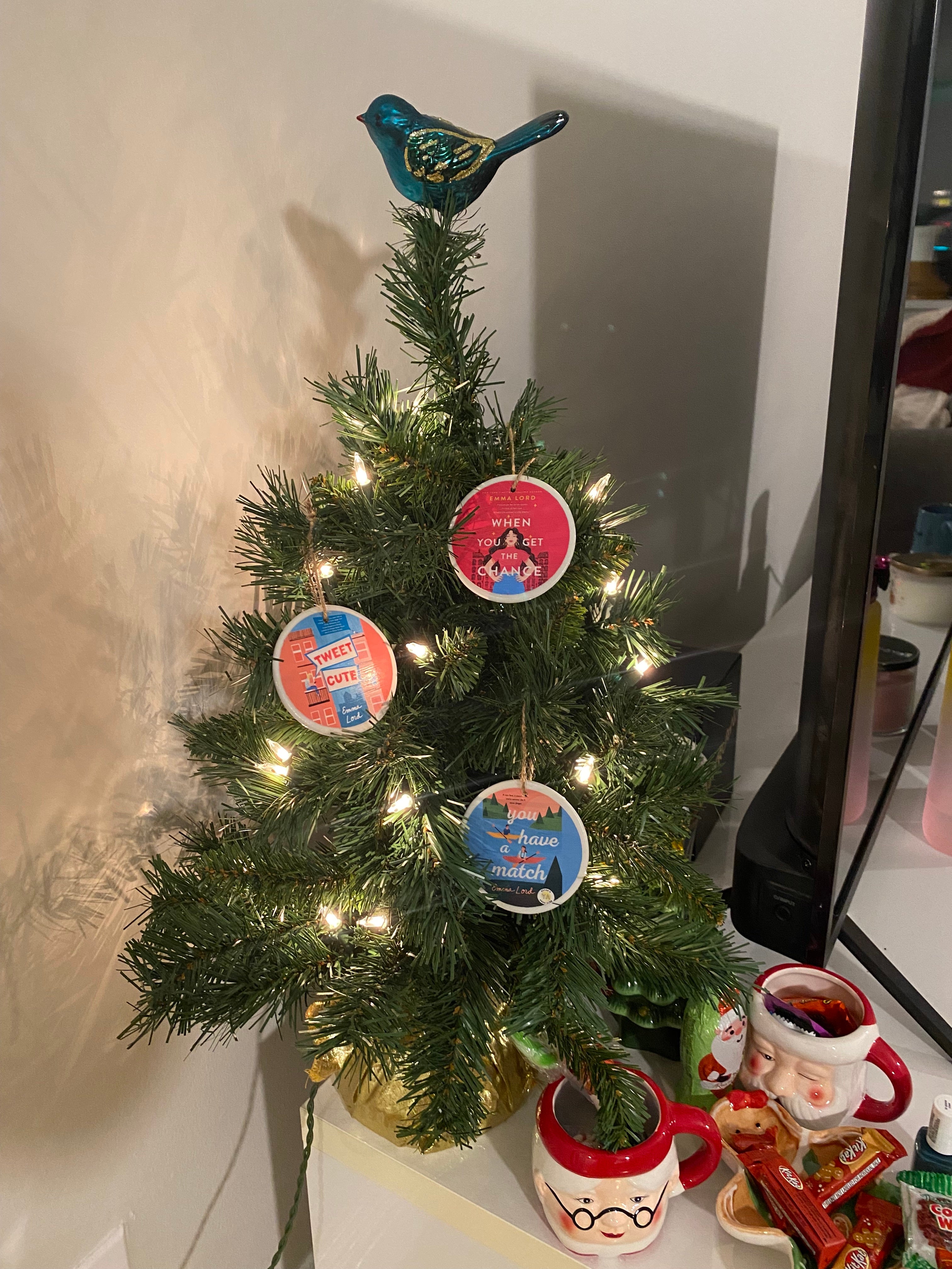 a tiny tree with three circle ornaments on it with emma lord's book covers on each one