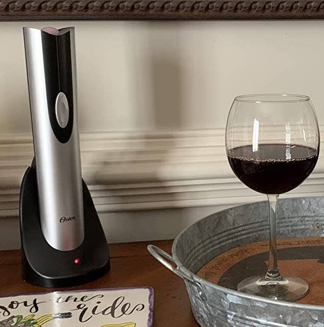 the silver and black wine opener next to a glass of red wine