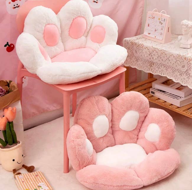 Pink and white paw-shaped pillows on chair and on the floor
