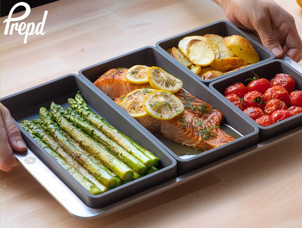 a model holding a sheet pan with four silicone dividers each filled with a different type of food