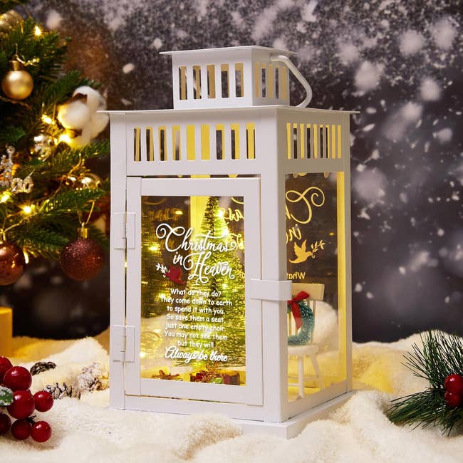 a white lantern lit up with a Christmas tree figure inside