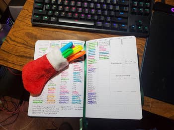 A reviewer's planner shown open with various notes, some highlighted and highlighters in a small pouch that looks like a Christmas stocking