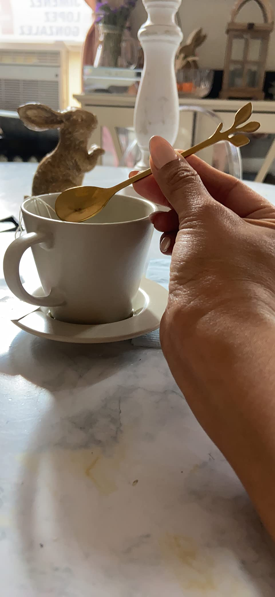 A manus  stirring a blistery  beverage successful  a teacup with a golden  spoon. A decorative rabbit and location  items are successful  the inheritance  connected  a table