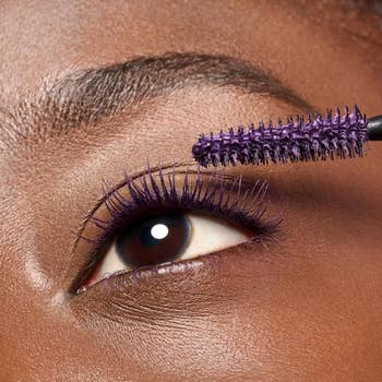 Close-up of an eye with purple mascara applied, showcasing eyelash enhancement in a makeup context