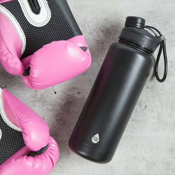 Pink boxing gloves adjacent  to a large, achromatic  h2o  vessel  with a loop grip  connected  a factual  surface