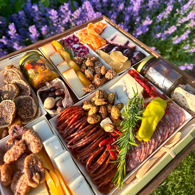 A gourmet charcuterie board with a variety of meats, cheeses, nuts, and fruits, presented outdoors