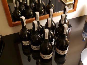 Nine bottles of sparkling vino  connected  a reflective surface, organized successful  rows with disposable   labels