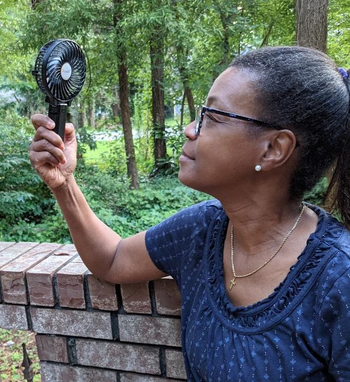 reviewer holding the black fan to their face