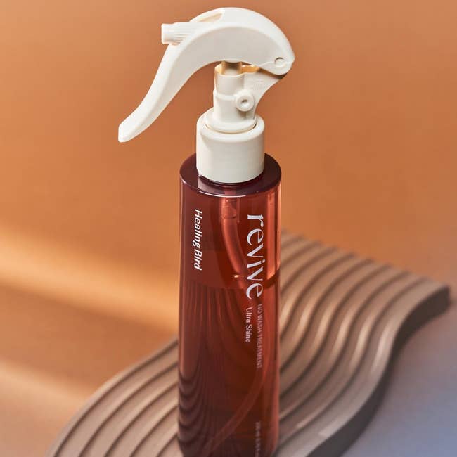 Revive Healing Bird hairsbreadth  styling spray vessel  with a unsocial   nozzle, acceptable   connected  a textured surface