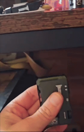 A idiosyncratic   uses a tiny  multi-tool to unfold a weapon  leaf  connected  a desk