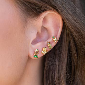 a model wearing four stud earrings inspired by the princess and the frog