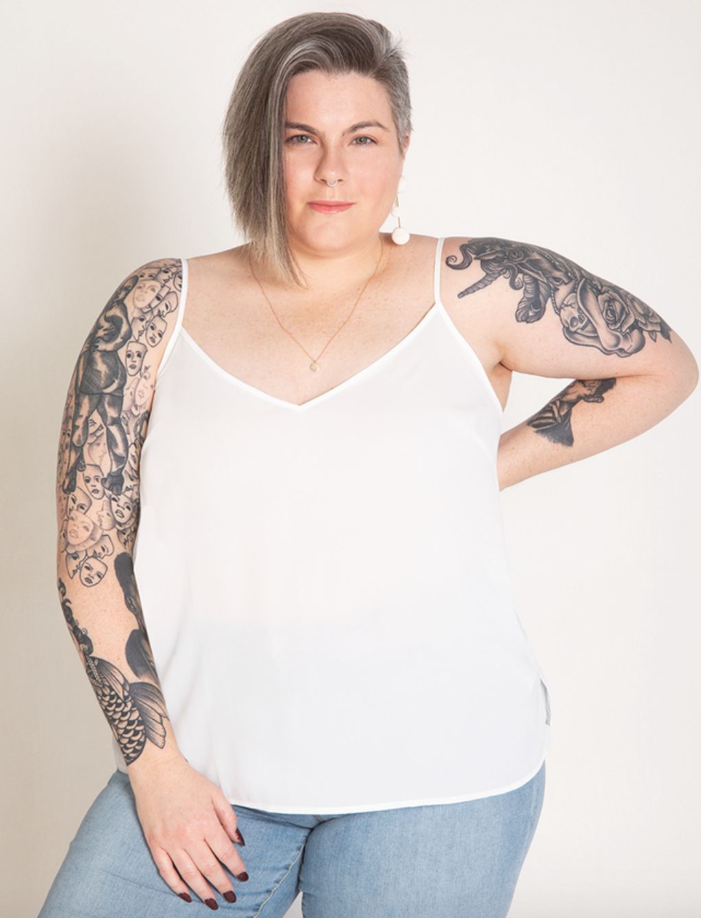 Model is wearing a white tank top and denim jeans
