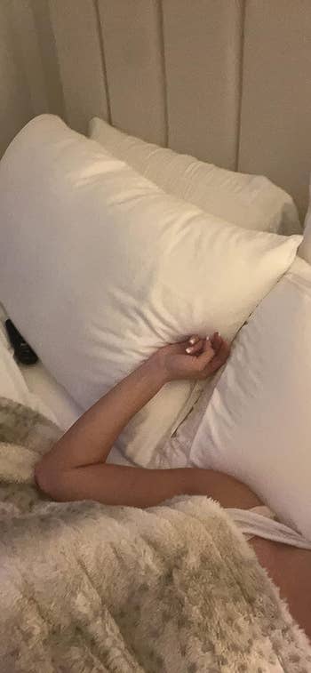 Reviewer with arm rest on the set of pillows in bed