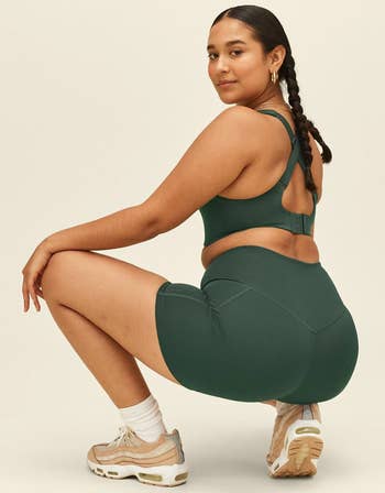 different model demonstrating a squat in the dark green high rise running shorts