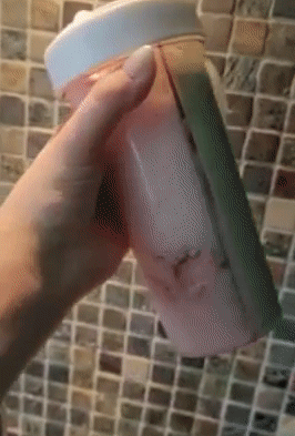 gif of reviewer turning the creative water cup filled with two beverages upside down to show that it doesn't leak
