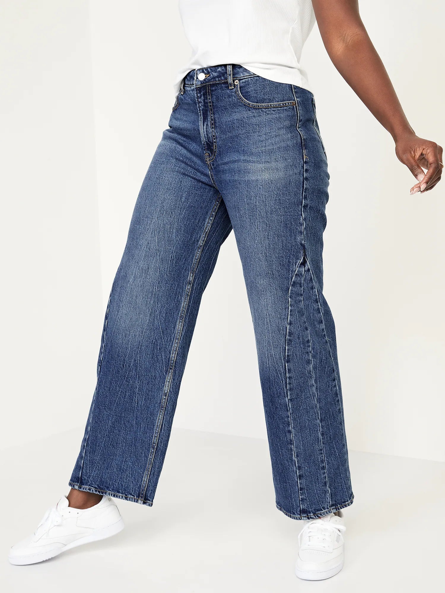 a model taking a step wearing the dark blue wide leg jeans with stitch detailing