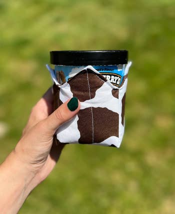 Model holding cow-printed ice cream cozy 