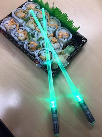 reviewer's glowing green chopsticks on top of sushi