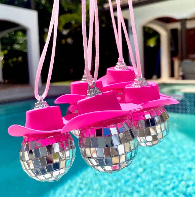 Small disco balls adorned with pinkish cowboy hats hanging connected a drawstring