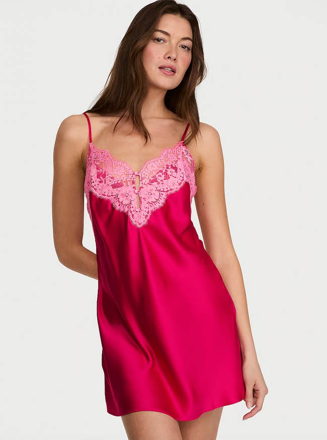 Model wearing a satin gaffe  formal  with lace detailing connected  the neckline