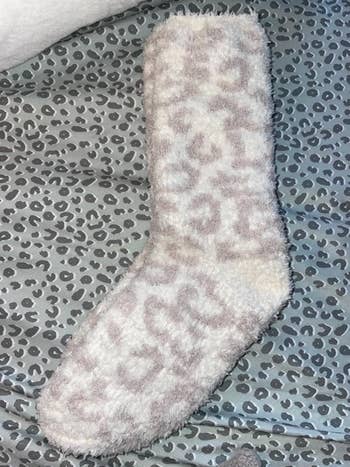 Fluffy sock with a leopard signifier   connected  a matching leopard people     cloth  background