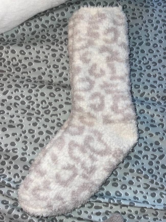 Fluffy sock with a leopard signifier   connected  a matching leopard people     cloth  background