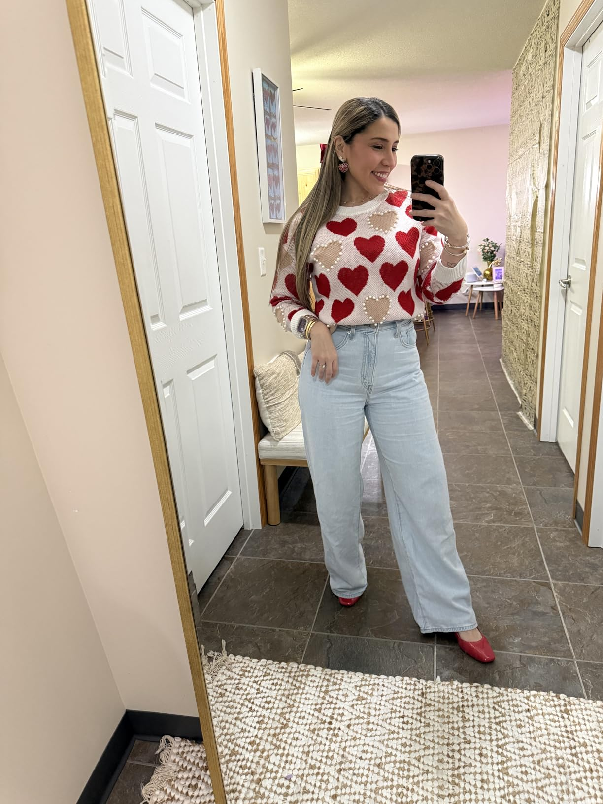 person successful  heart-patterned sweater, airy  jeans, and reddish  shoes taking a selfie successful  a hallway, showcases chic casual style