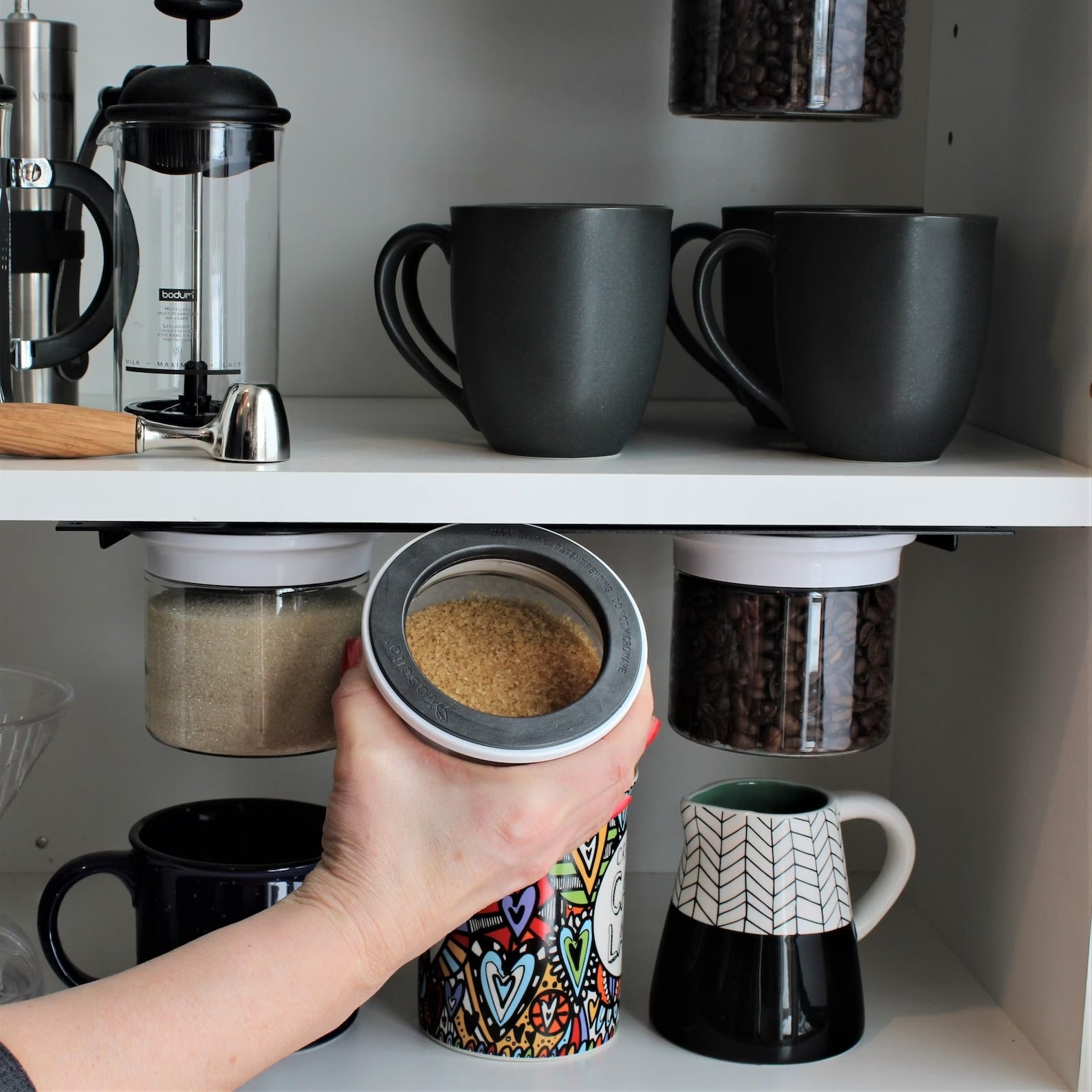 person showing three canisters being used for sugar and coffee beans with hand pulling one out