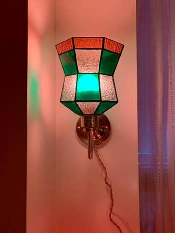 Stained solid  partition  lamp with geometric design, featuring greenish  and frosted panels, casting colorful airy  successful  a warmly lit room