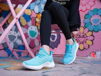 Model sitting while wearing blue SDolphin sneakers 