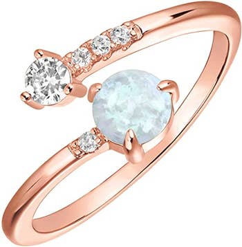 Open rose gold band with clear gems on one side and larger opalescent gem on other
