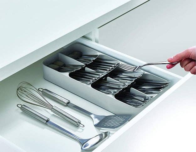 hand slides fork out of silver silverware holder in white drawer