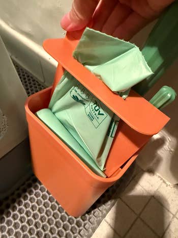 Hand opening the trash container compartment connected the litter scooper