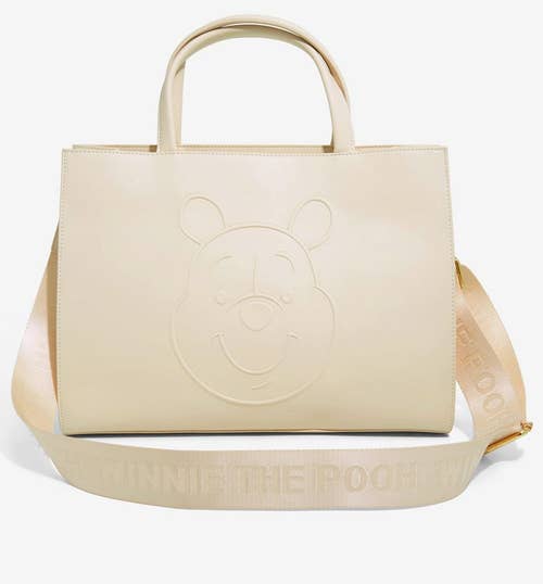 off white tote with pooh face embossed and winnie the pooh written on fabric crossbody strap