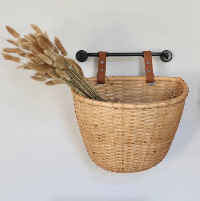 A wall mounted woven storage basket is shown
