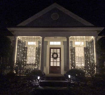 reviewer photo of two of the string light panels lit up between columns on their front porch
